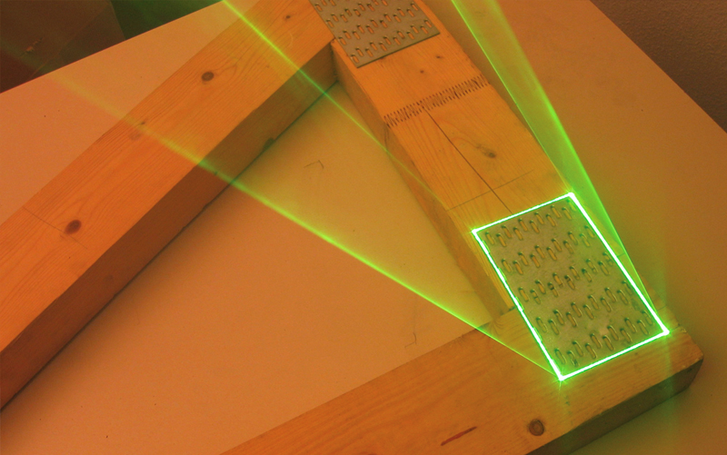 Holzverbindung mit Metallplatten in der Fertigung – grüne SL-Laser Linien markieren exakte Position und Ausrichtung der Bauteile.