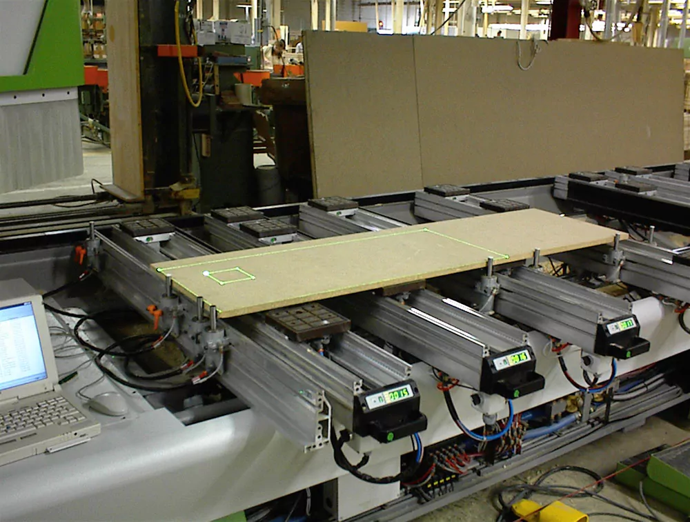 Bild zeigt eine CNC Maschine, bei der grüne Laserlinien die exakte Position von Holzfertigteilen anzeigen 3