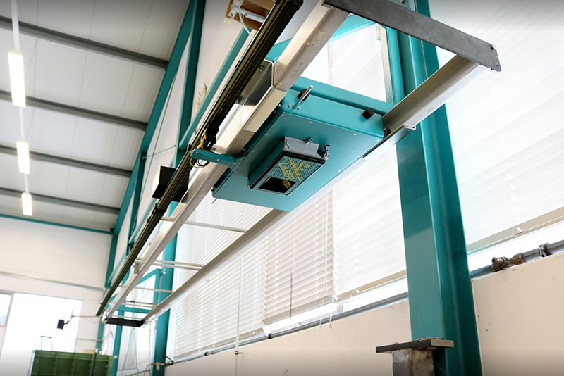 SL-Lasergerät an einer Deckenschiene montiert, ermöglicht präzise Laserprojektionen in der Fertigungshalle.