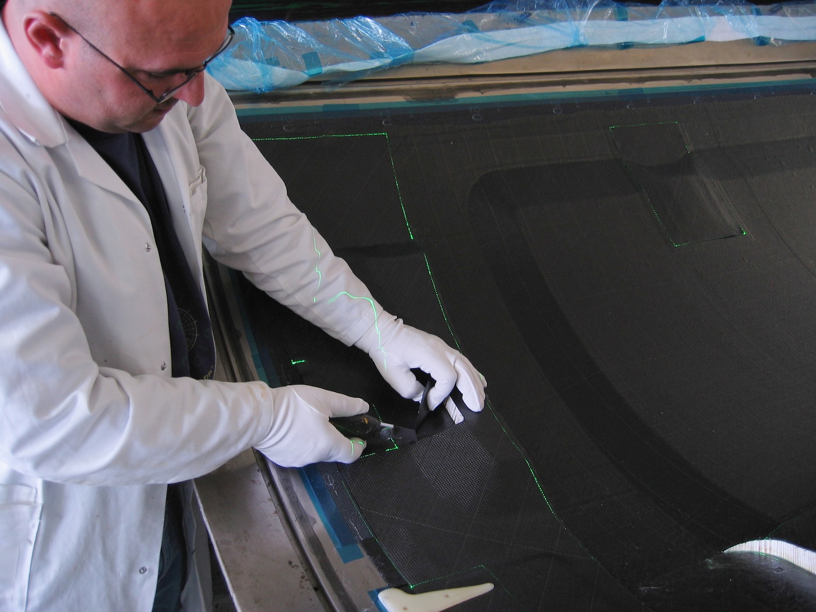 Employee cuts materials precisely along projected green laser lines