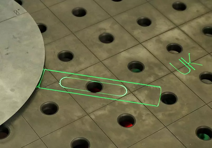 Metallarbeitsfläche, auf der grüne Laserlinien die exakte Position und Form eines Bauteils projizieren 1