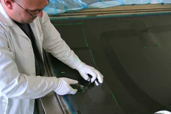 Mitarbeiter schneidet passgenau Materialien entlang projizierter grüner Laserlinien 4