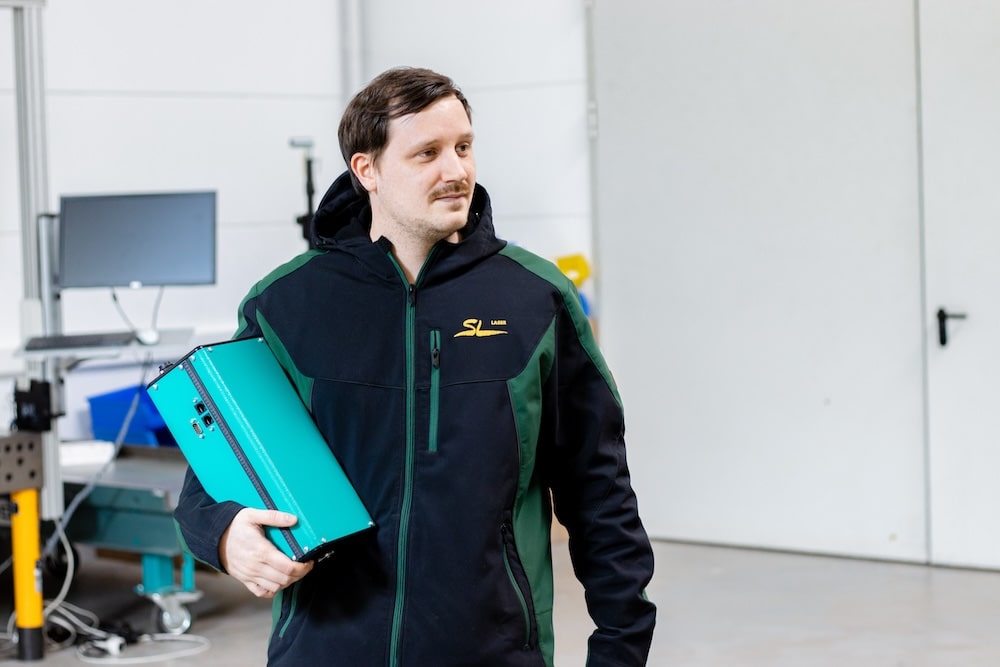 Mitarbeiter trägt ein Lasersystem durch die Produktionshalle – mobiler Einsatz von Laser in der Fertigung
