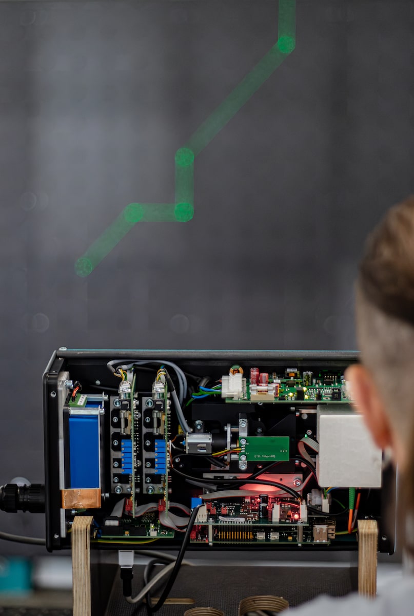 Opened SL Laser projector with visible electronic components – technician inspects the parts while green laser lines are projected.
