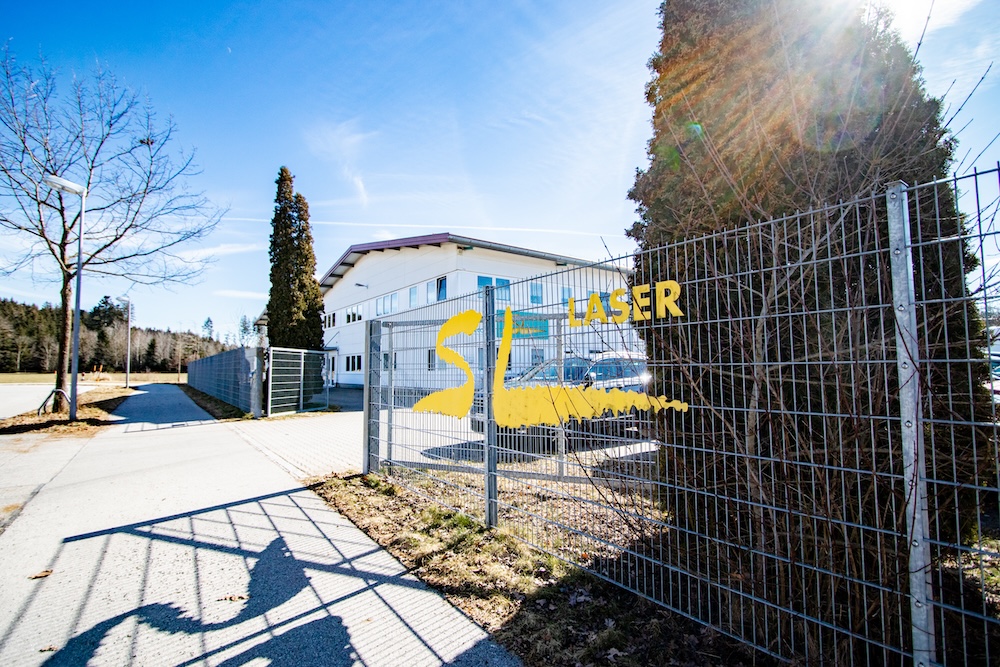 SL Laser logo on a metal fence at the entrance to the company premises