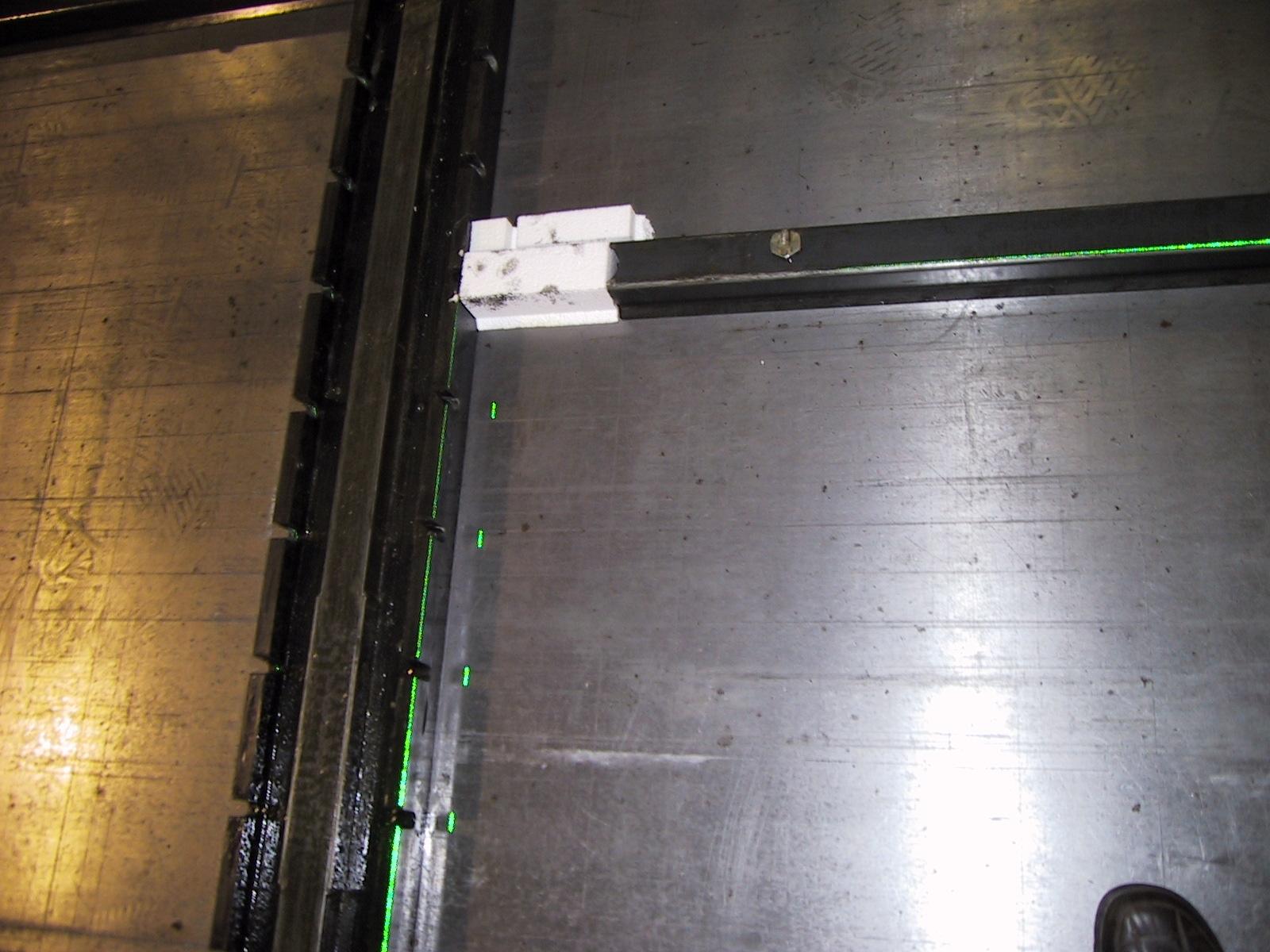 Metal formwork with inserted spacers is precisely positioned by green laser lines.