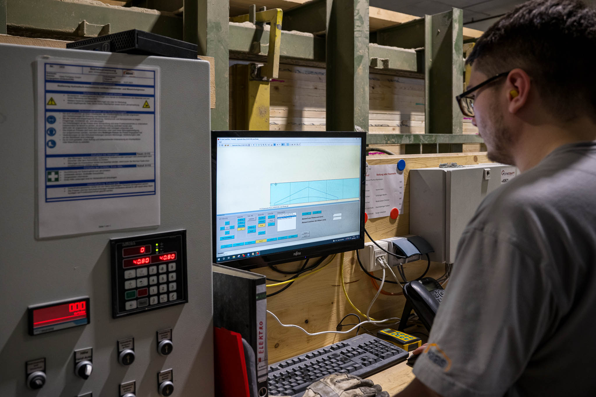 Un collaborateur surveille le pilotage d'une installation laser SL depuis un poste de travail informatique. L'écran affiche une interface logicielle avec les données de projection.