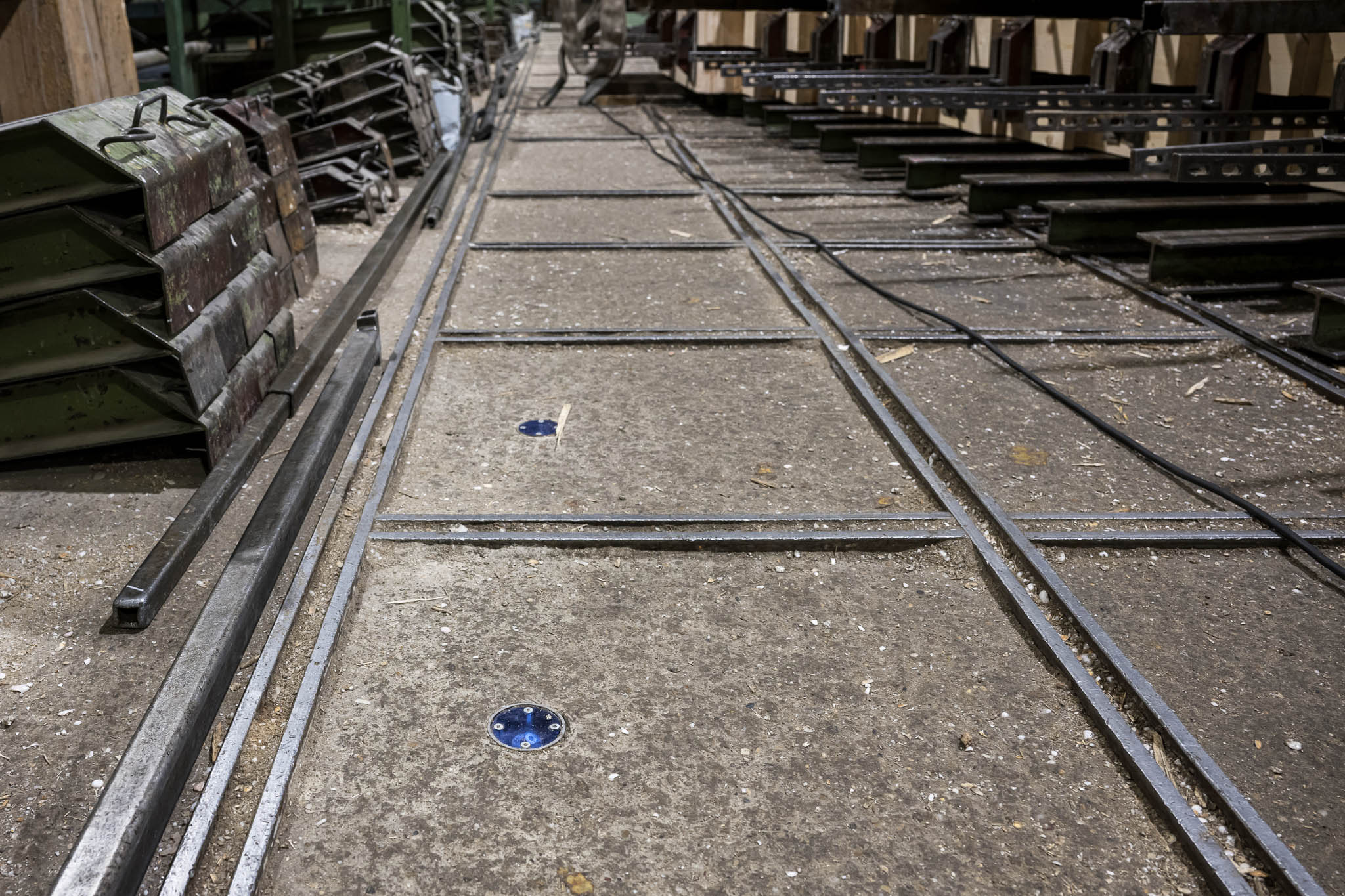 Les marquages au sol avec réflecteurs bleus dans un hall de production servent de points de référence pour l'alignement précis des systèmes laser SL.