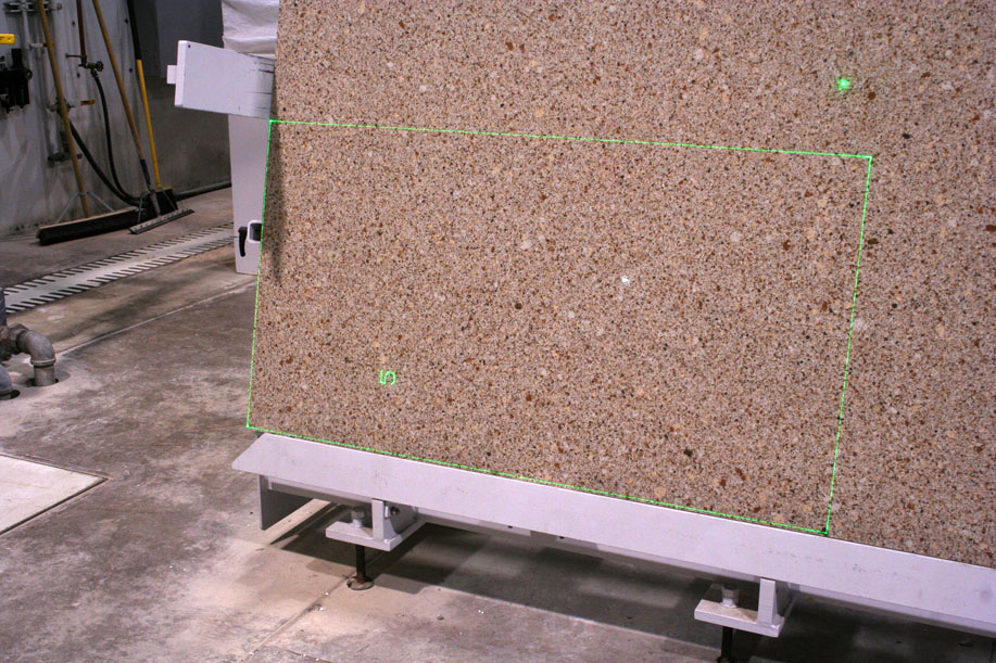 Large stone slab in a production hall – green laser lines from SL-Laser mark precise cutout positions.