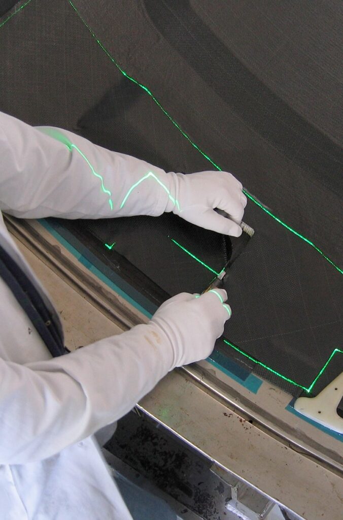 L'employé coupe des matériaux composites en carbone ou en fibre le long de lignes laser projetées avec la plus grande précision de l'industrie des composites