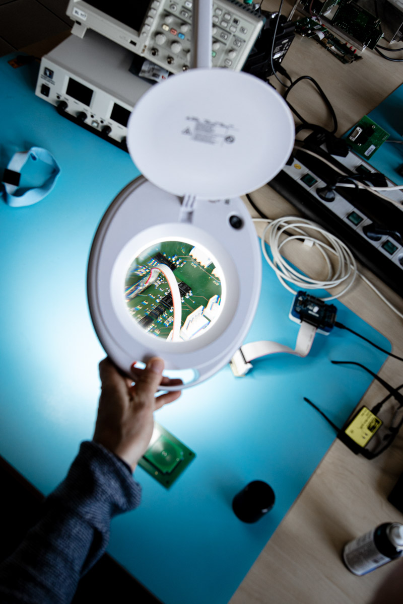 Un employé vérifie un circuit imprimé avec une loupe