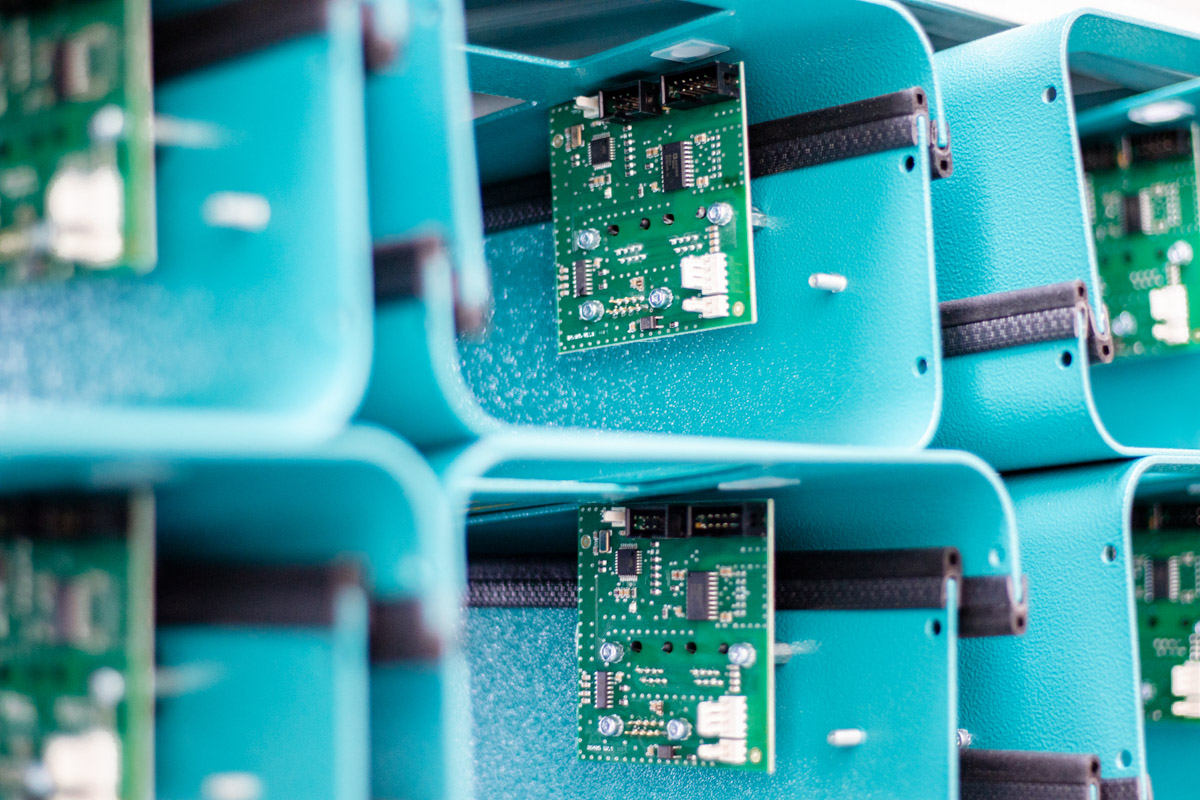 Detailaufnahme von grünen Leiterplatten in blauen Gehäusen – Elektronikkomponenten von SL-Laser.