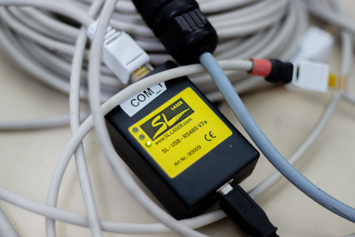 Netzteil in schwarz mit einem SL Laser Typenschild und grauen Kabel