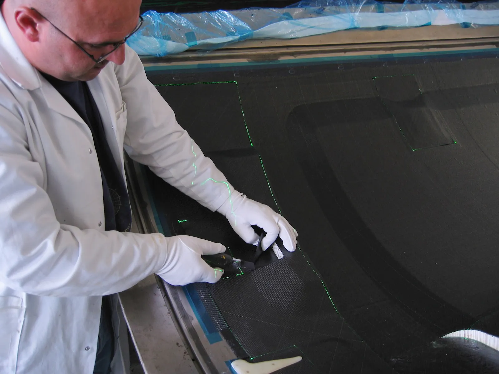 Mitarbeiter schneidet passgenau Materialien entlang projizierter grüner Laserlinien 4